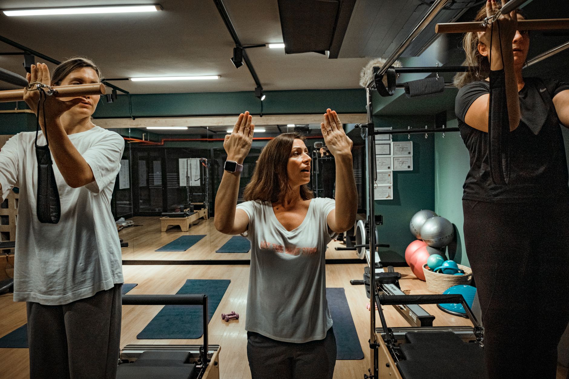 professional instructor guiding a student on pilates reformer in a bright studio