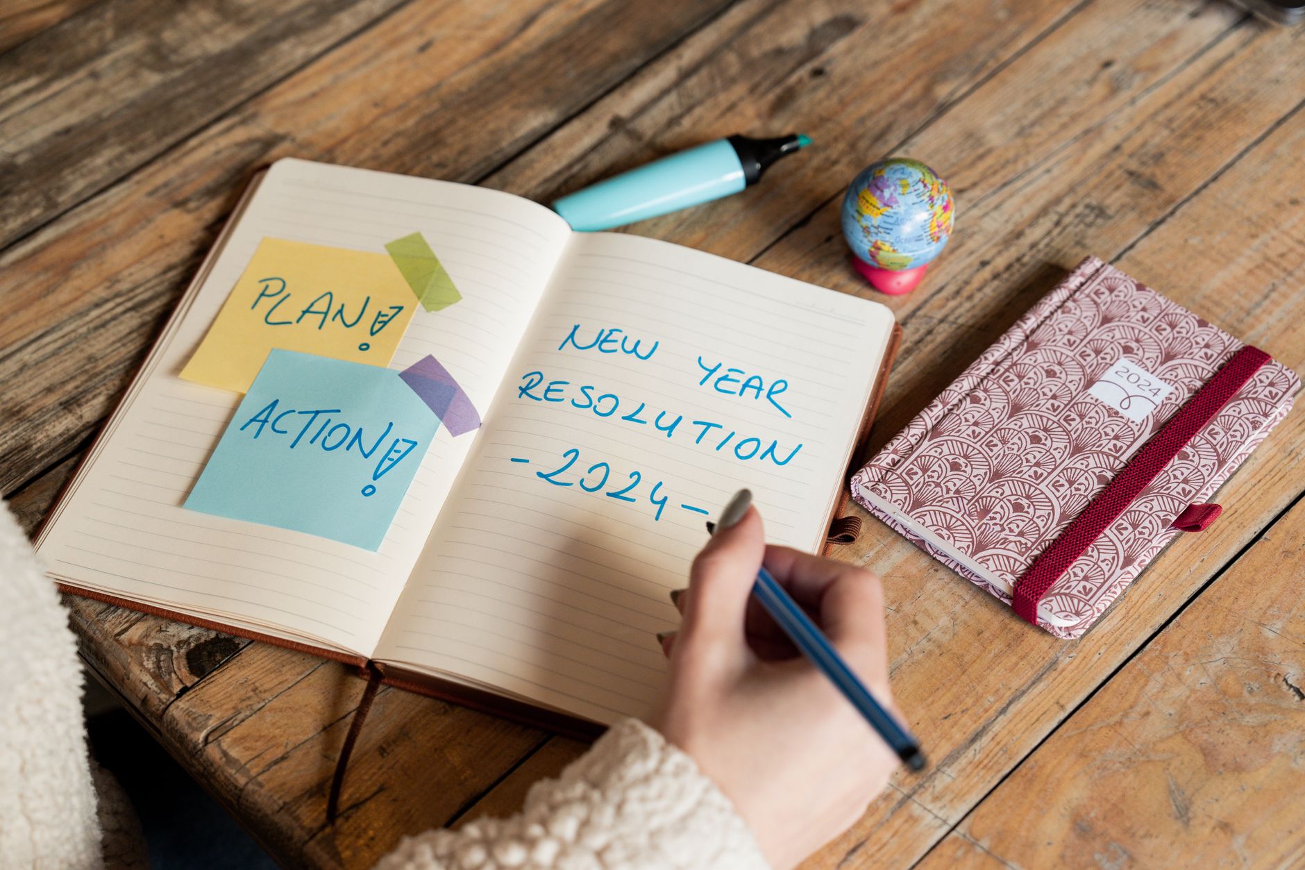 A person planning a small event with a notebook and some decorative items on a w