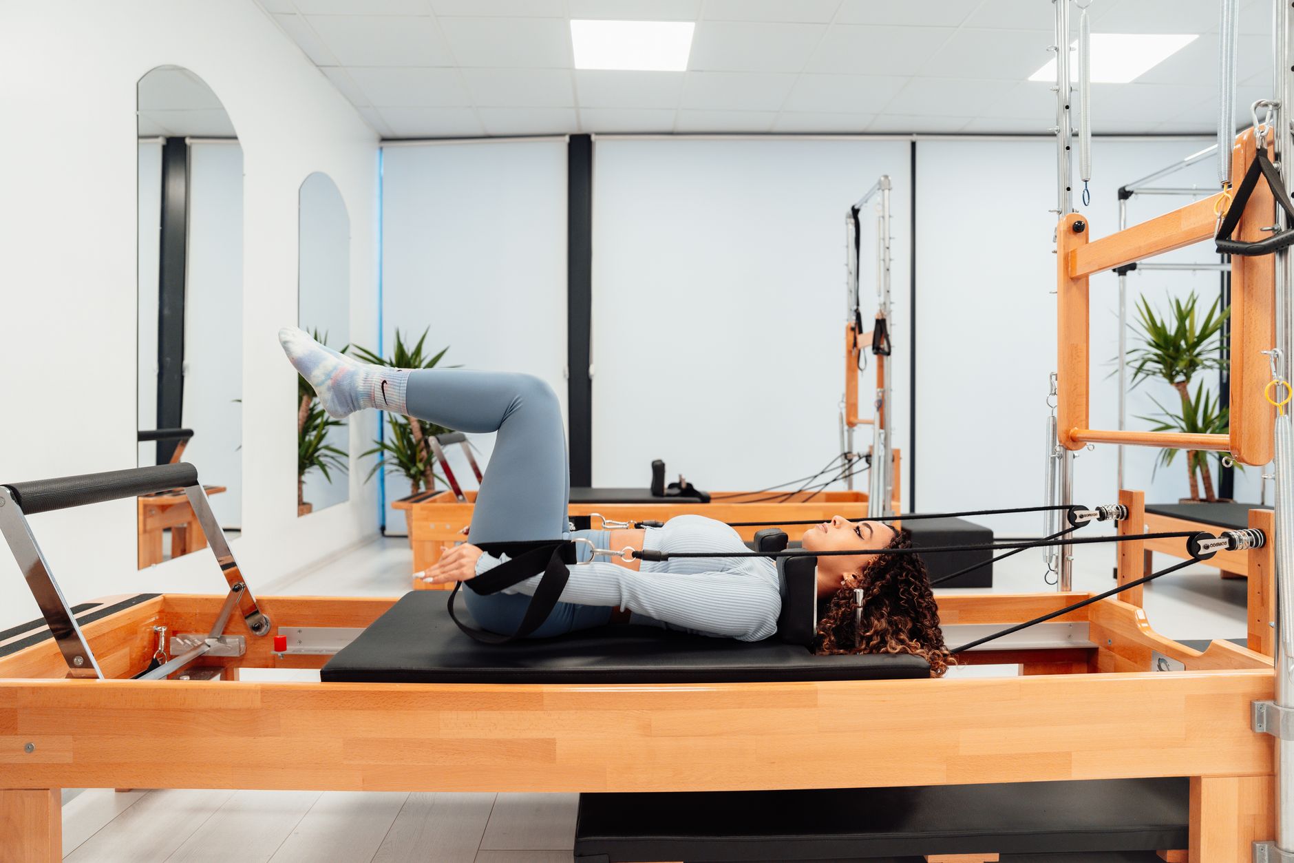 A person doing pilates exercises on a reformer machine with a focus on spine ali