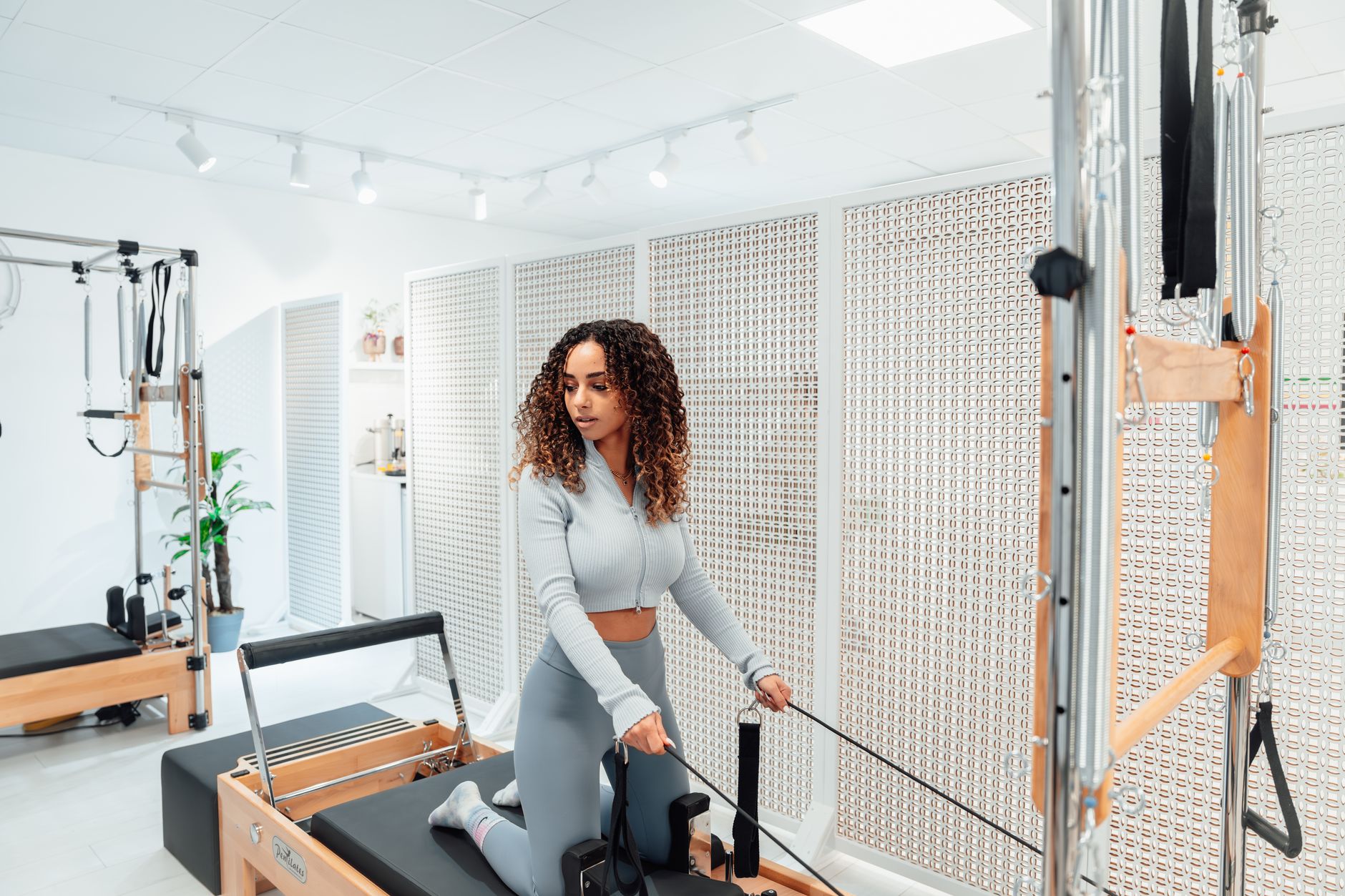 woman doing reformer pilates exercise in a modern bright studio