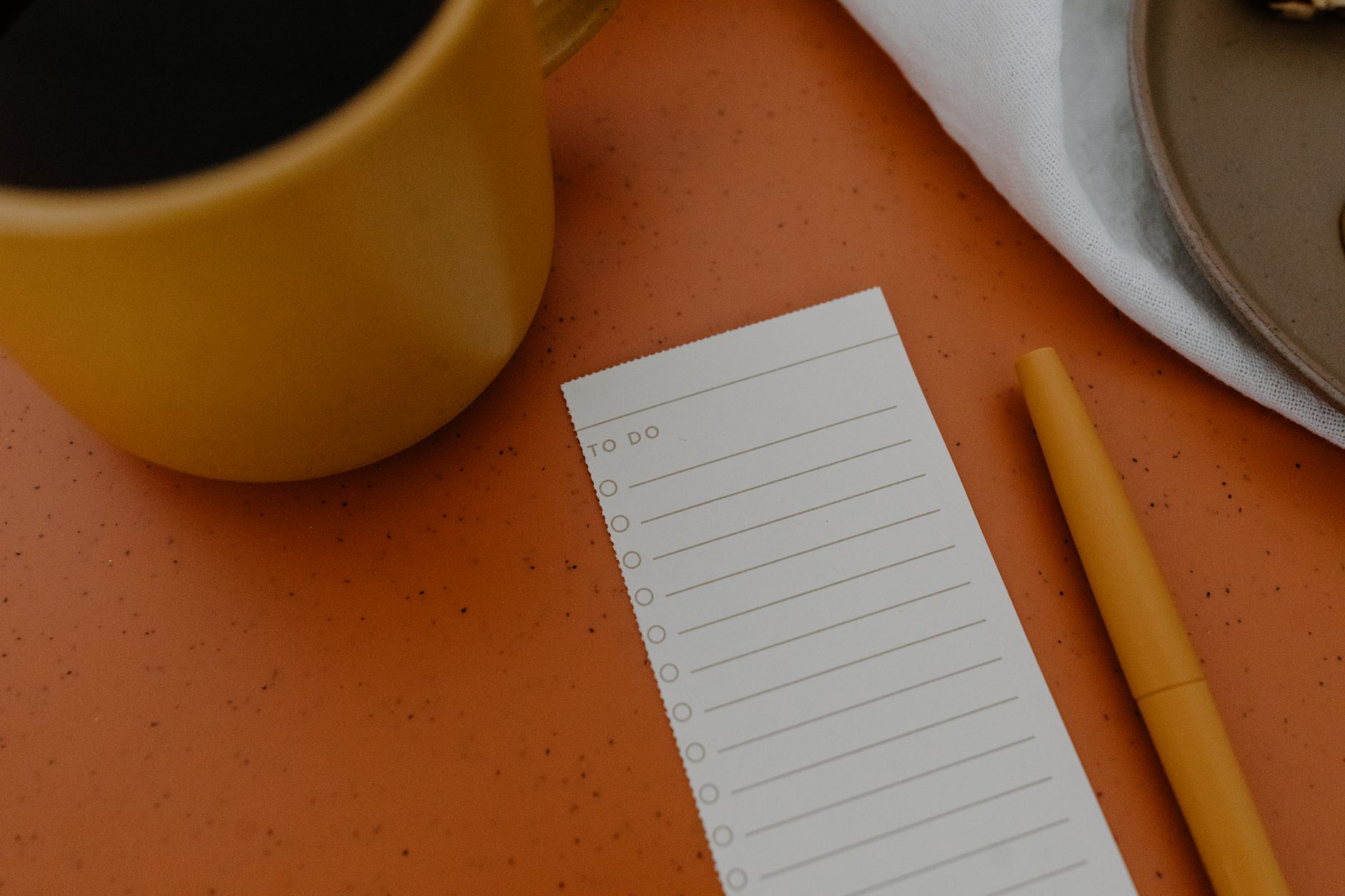 A notebook with a checklist and coffee on a wooden table warm lighting