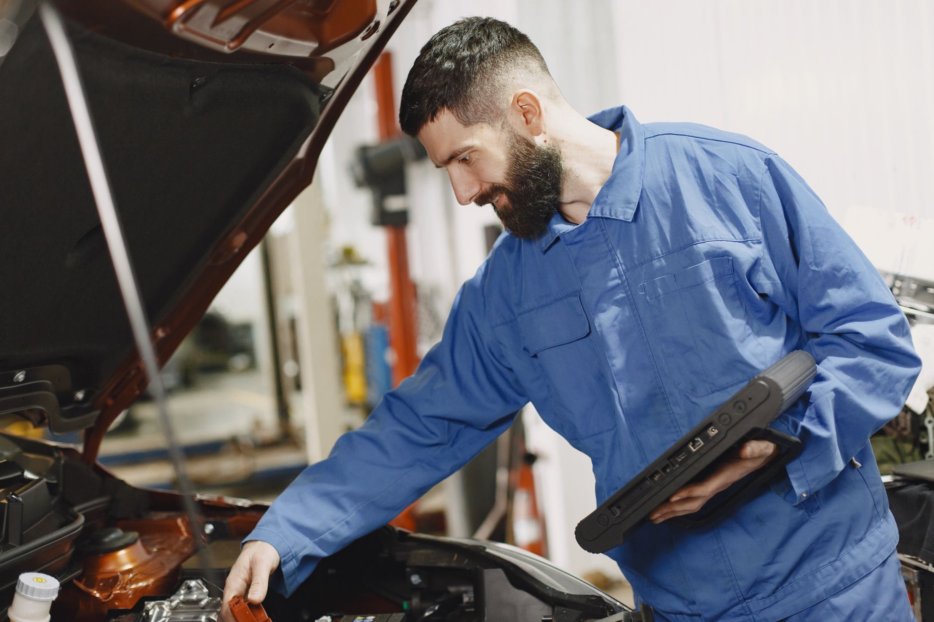 mechanic checking car engine with laptop diagnostic tool