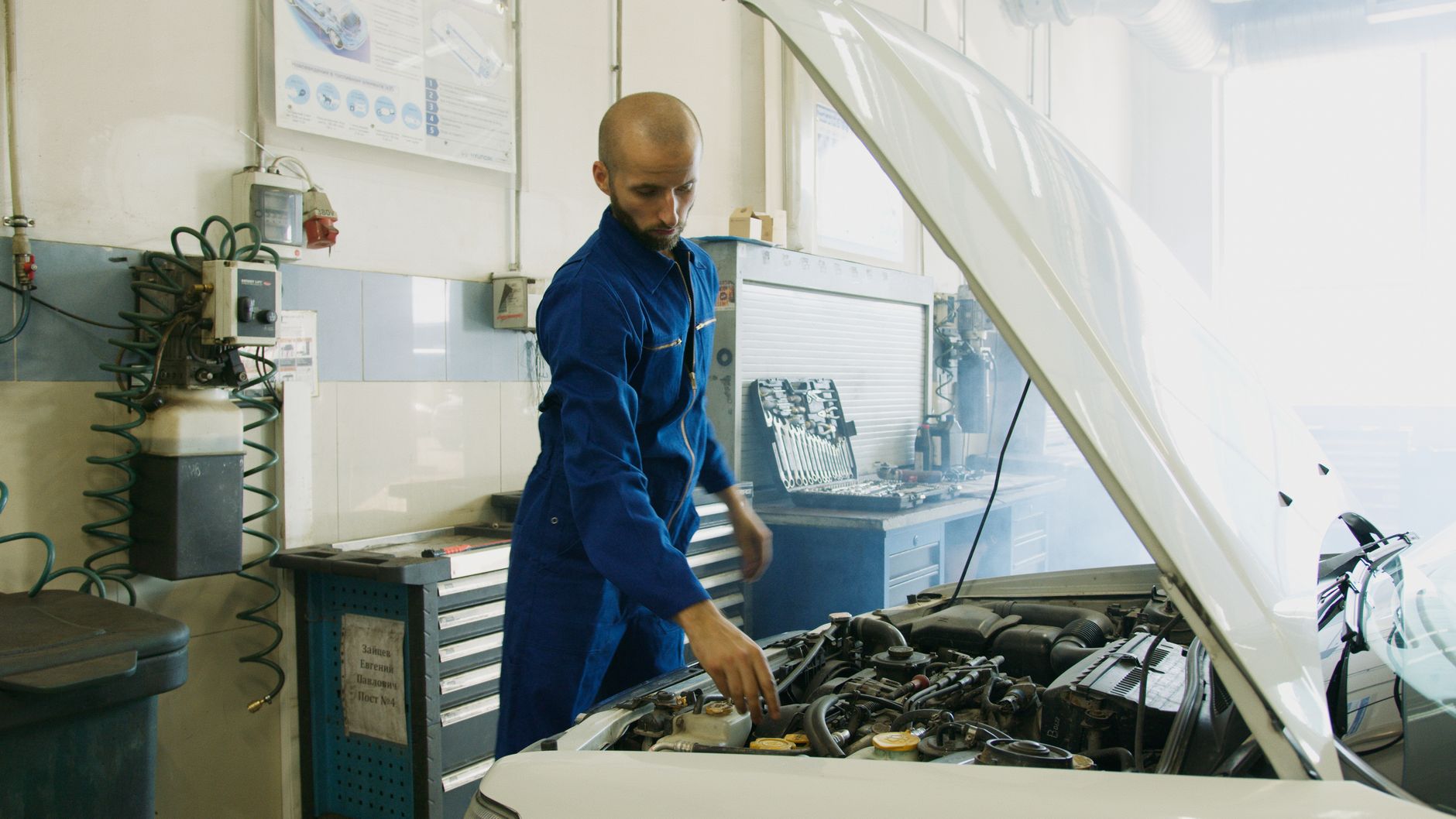 mechanic inspecting car engine in professional garage